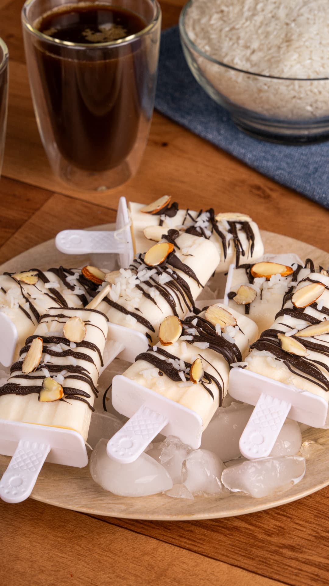 Paletas con chocolate, coco y almendra sobre plato de madera
