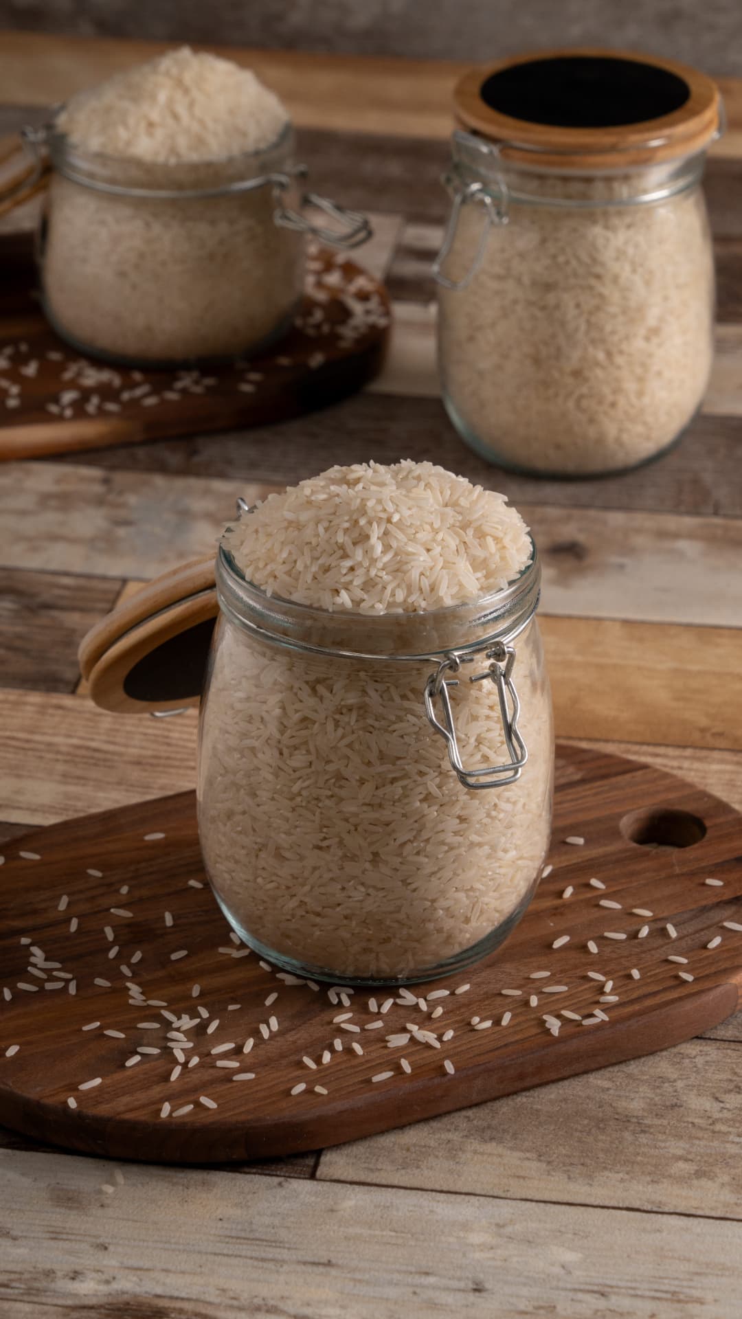 Frascos de vidrio con tapas de madera llenos de arroz sobre tabla