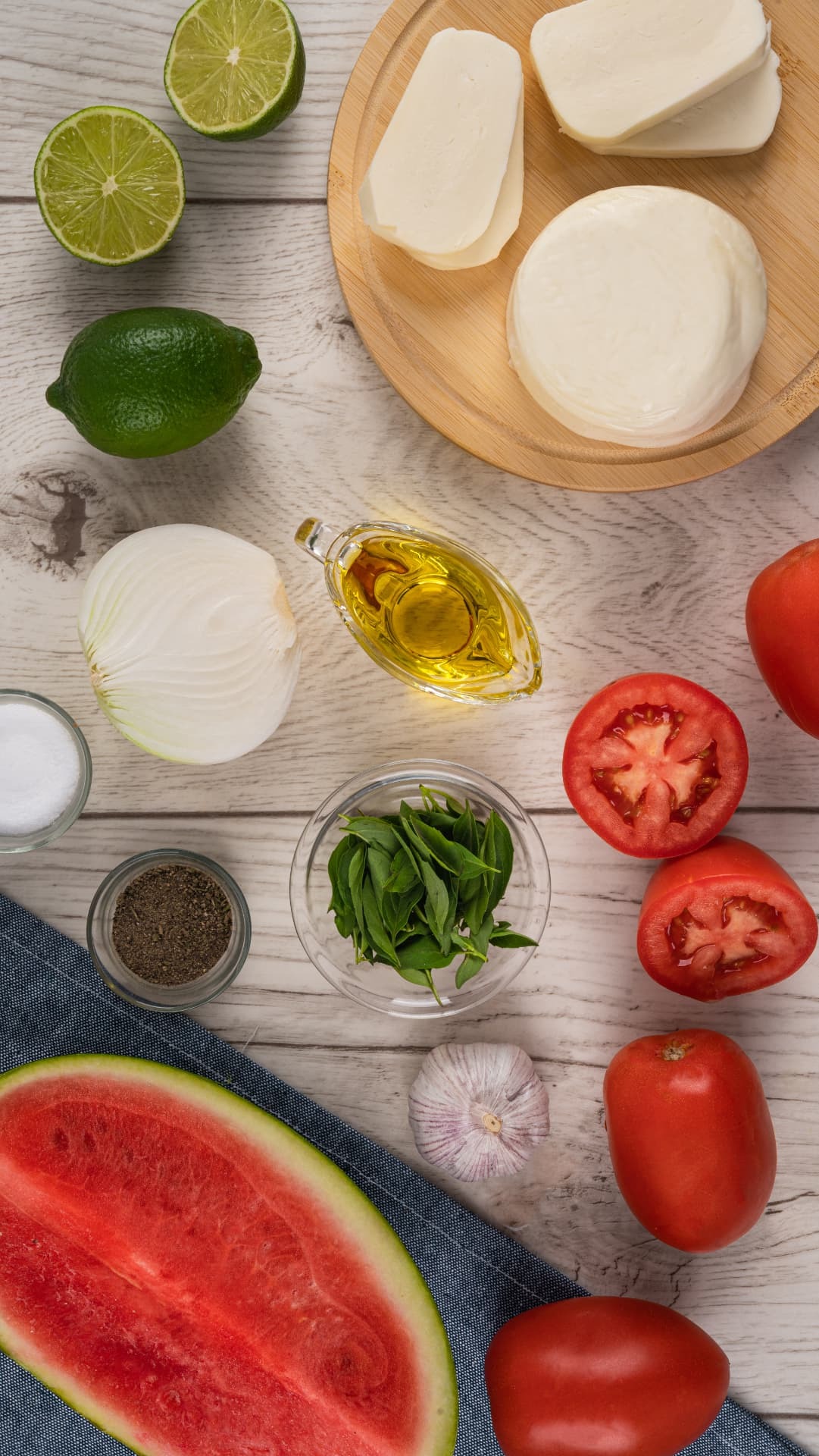 Mozzarella, jitomate, sandía, limón y hierbas organizados para preparar una receta