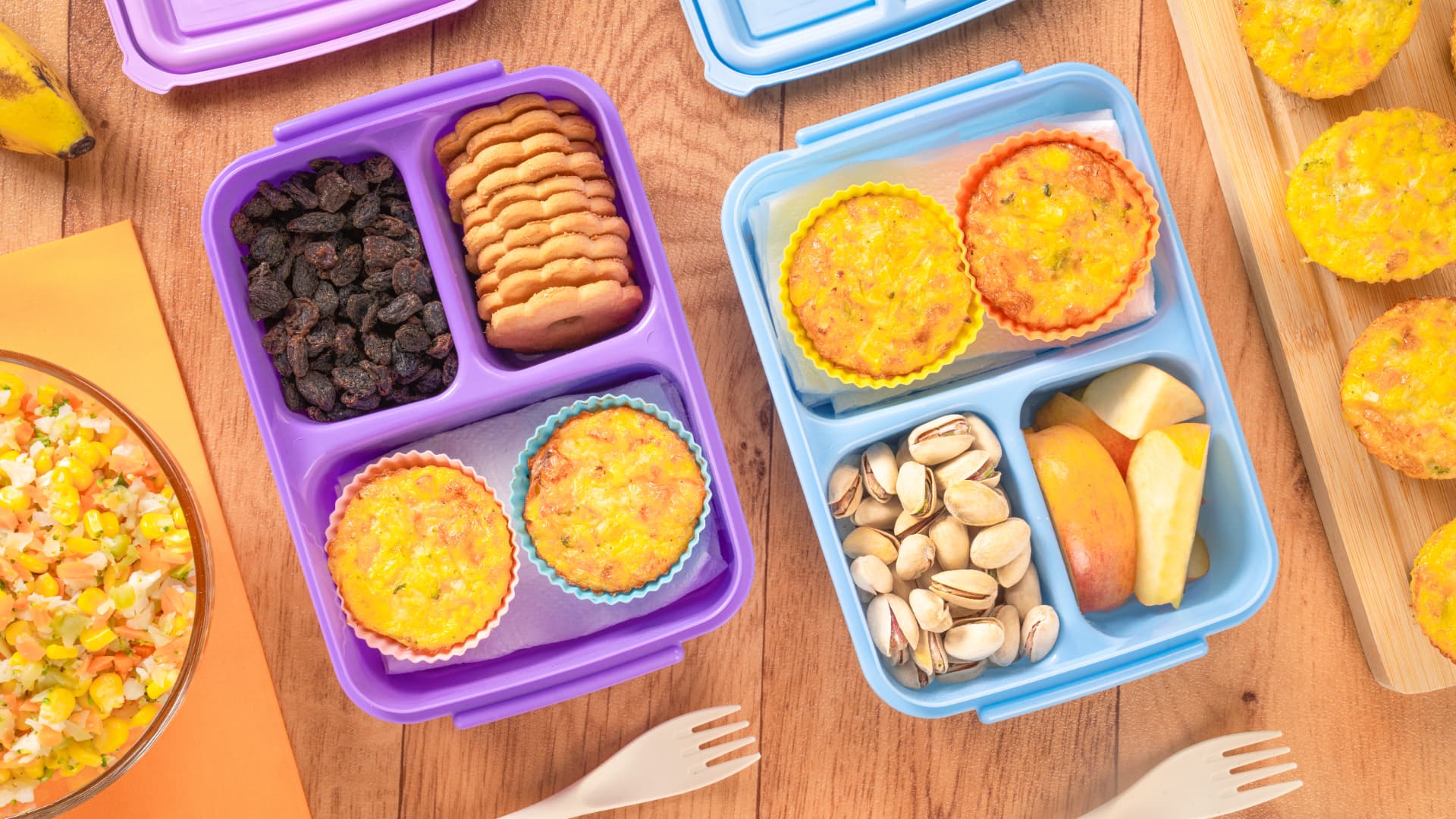 Viandas con muffins de huevo y verduras, galletas, pistaches y manzana, vista cenital