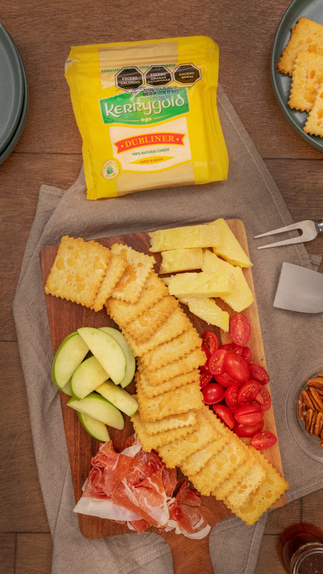 Crackers de queso Kerrygold con manzana, tomates y queso sobre tabla de madera
